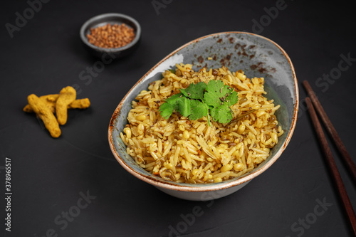 Kichari decorated with parsley leaves next to cardamom and turmeric photo