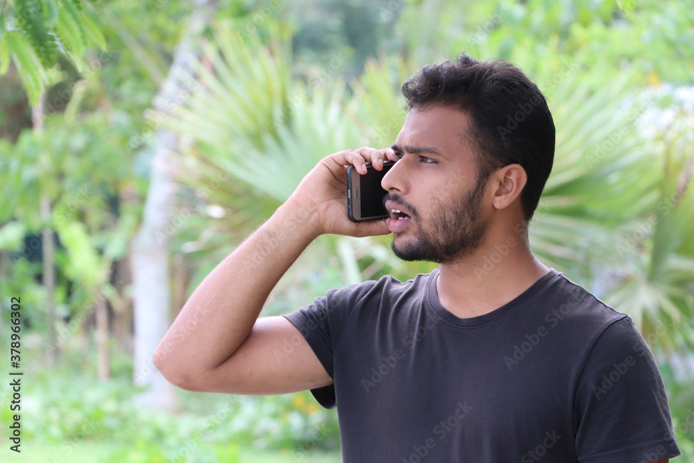 Portrait of a young man talking on mobile phone and looking shocked Portrait of a young man talking on mobile phone and looking shocked