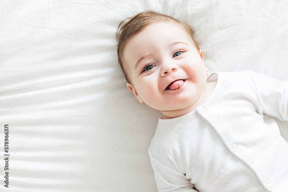 Newborn toddler boy laughing on the bed and looking at the camera Newborn toddler boy laughing on the bed and looking at the camera