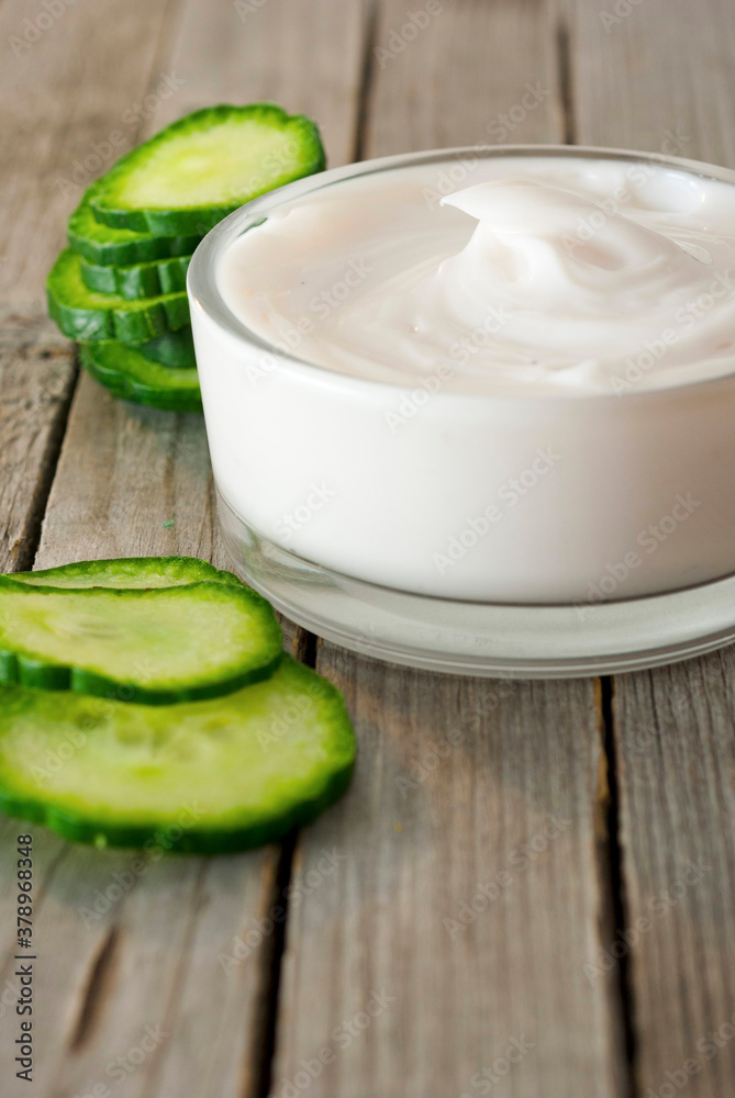 Face cream and cucumber slices on old wooden table Face cream and cucumber slices on old wooden table