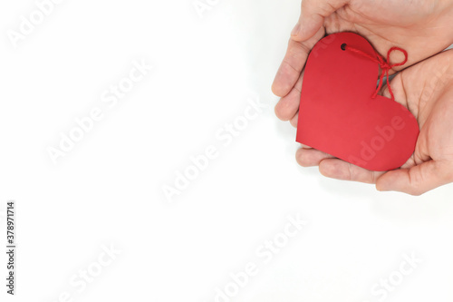 Top view of young male cupped hands holding a red heart shape tag in white background. Non-materialistic love is the best gift for birthday, christmas, mother's, father's and valentine's day concept.