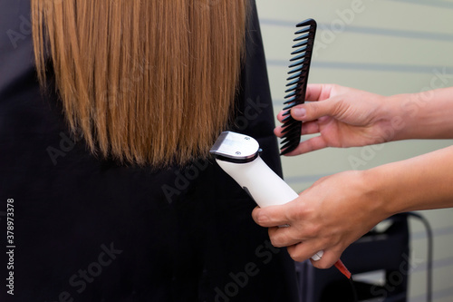 Hairdresser with a hair machine. cutting off split ends of hair with a clipper. close up.