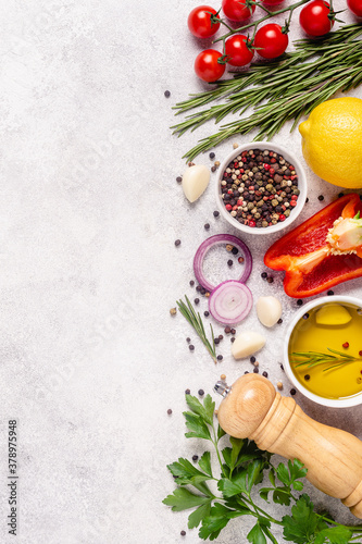 Herbs and condiments on light stone background.