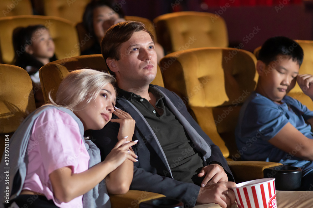 Obraz premium Young woman with friends watching movie in cinema . diversity people watching movie in cinema theater with popcorn and drinks.