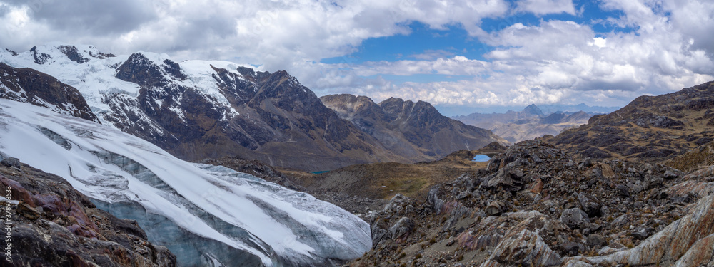 Obraz premium Panorama mountain landscape with a beautiful blue cloudy sky with blured clouds, ice, snow lake and rocks in Huaytapallana mountain range, huancayo, peru
