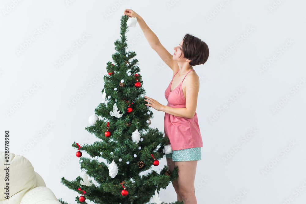 Beautiful young woman decorating a Christmas tree. Holidays and celebrations concept. Beautiful young woman decorating a Christmas tree. Holidays and celebrations concept.