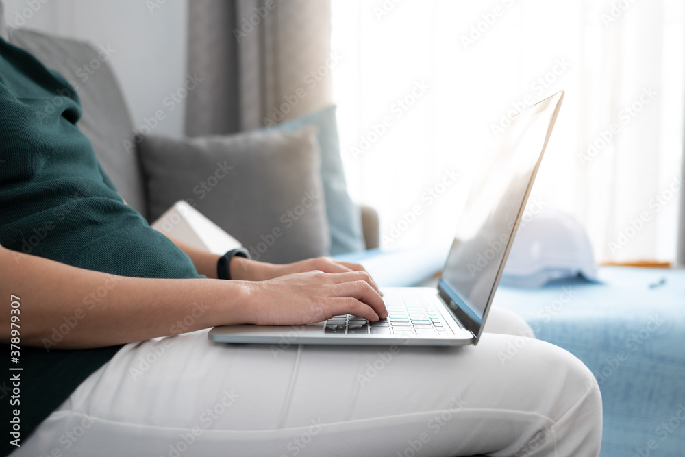 Fototapeta premium Close up engineer woman hand is using laptop for work with blueprint and hard hat background.