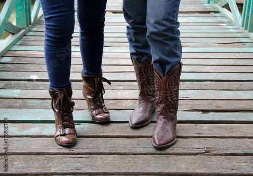 People wear jeans to wear boots walking on a wooden bridge. 
