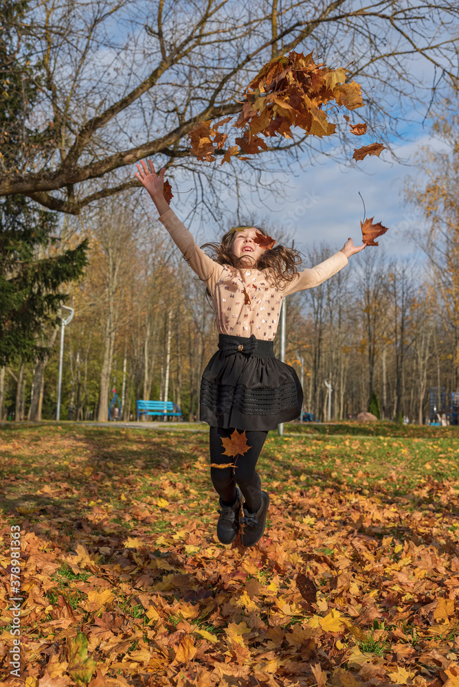 A cheerful girl throws up fallen leaves in the park. A cheerful girl throws up fallen leaves in the park.