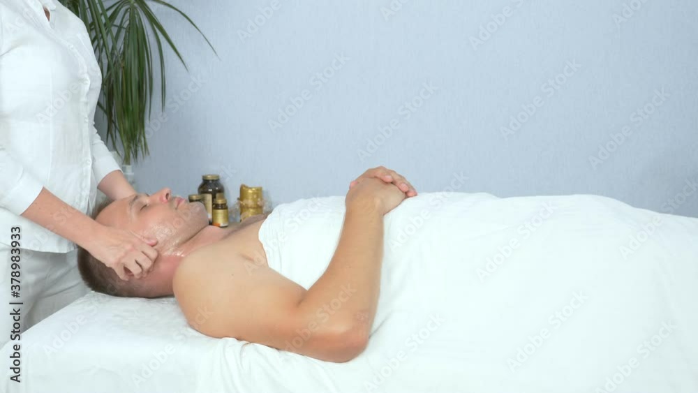 masseuse makes a cosmetic facial massage to a man in a spa salon