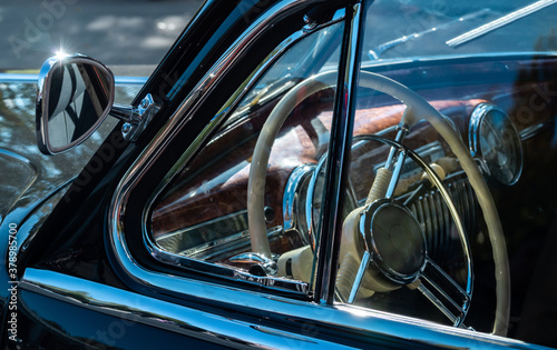 Steering wheel of an old classic car. Interior of a vintage car. Color image of the dashboard of a retro car. Close-up view of a classic vintage car. Retro car fragment. © Evgesha
