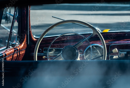 Steering wheel of an old classic car. Interior of a vintage car. Color image of the dashboard of a retro car. Close-up view of a classic vintage car. Retro car fragment.
