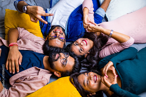 four indian friends lying down on the floor with pillows