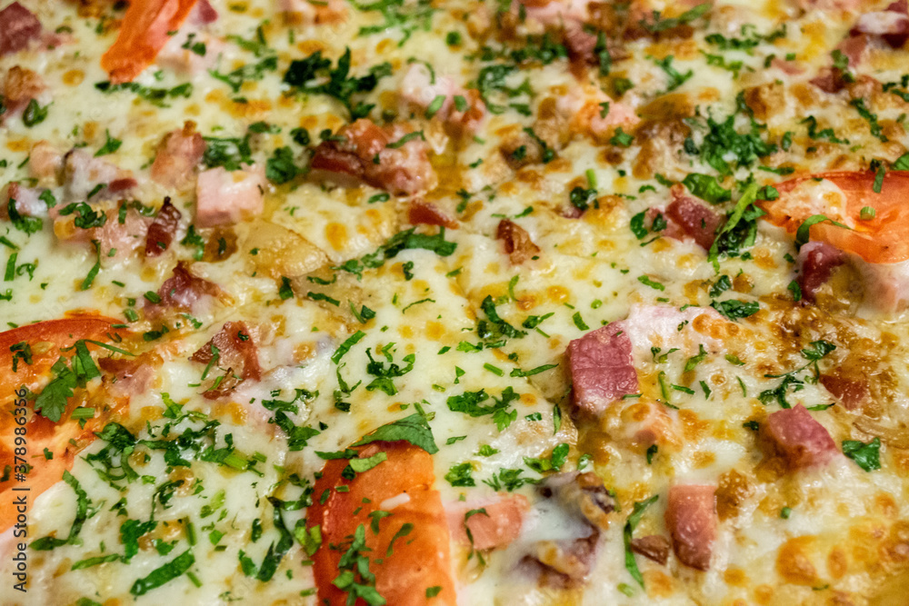 Close-up of pizza with ham, cheese, tomatoes and herbs and bacon. Food background Close-up of pizza with ham, cheese, tomatoes and herbs and bacon. Food background