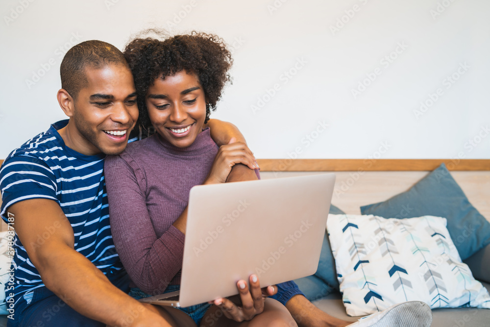 Young couple using laptop on couch at home. Young couple using laptop on couch at home.