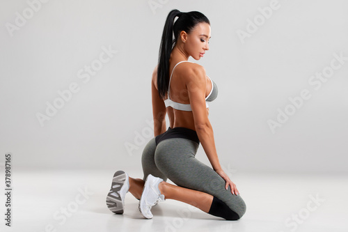 Beautiful athletic girl, sexy fitness woman in leggings on the gray background