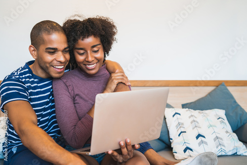 Young couple using laptop on couch at home.