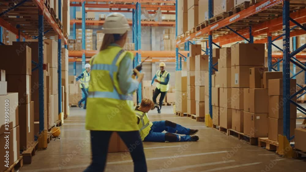 Warehouse Worker Has Work Related Accident Falls while Trying to Pick Up Cardboard Box from the Shelf. Colleagues Call for Help and Medical Assistance. Injury at Work. Slow Motion