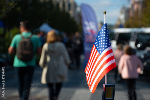 American flag waving on the car on the 4th, thanksgiving day  of July or during United States Presidential election 2020, Trump vs Biden, 11 September, with car on background with voters or electors photo