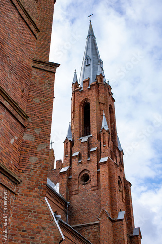 Red brick church. Brick tower with a cross on the background of the sky with clouds. Church of the Nativity of the Blessed Virgin Mary, Belarus, Vidzy photo