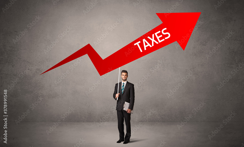 Fototapeta premium Young business person in casual holding road sign with TAXES inscription, business direction concept