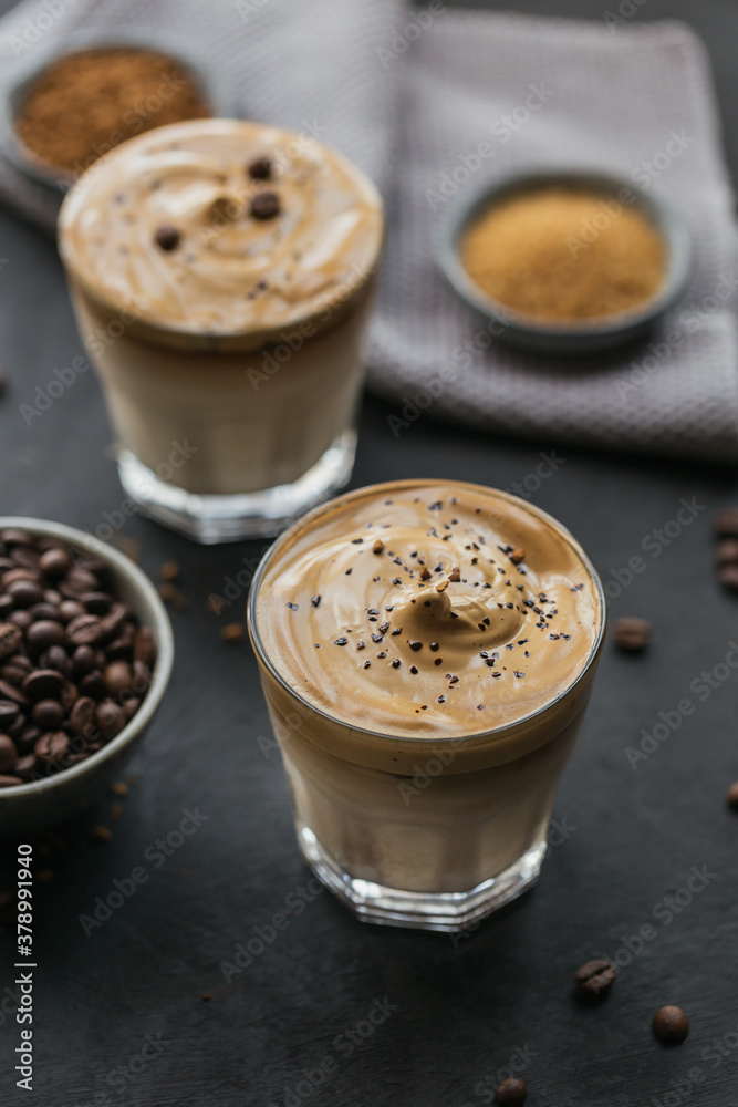 Glass of Iced Dalgona Coffee, trendy fluffy creamy whipped coffee and milk on black background. Glass of Iced Dalgona Coffee, trendy fluffy creamy whipped coffee and milk on black background.