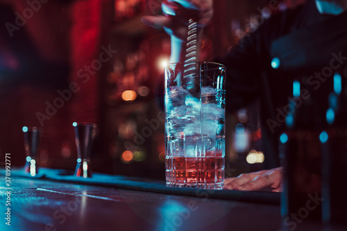 Detail of unknown bartender mixing cocktail in pub