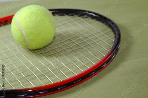 Tennis racket with ball on a green background © Jos