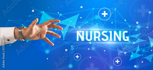 Close-Up of cropped hand pointing at NURSING inscription, medical concept