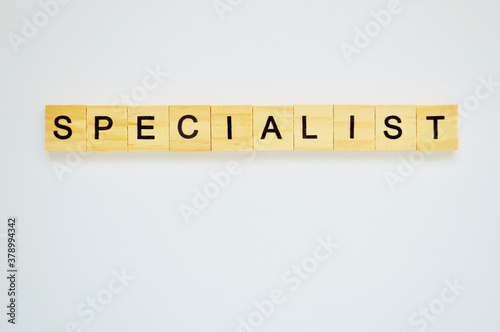 Word specialist. Wooden blocks with lettering on top of white background. Top view of wooden blocks with letters on white surface