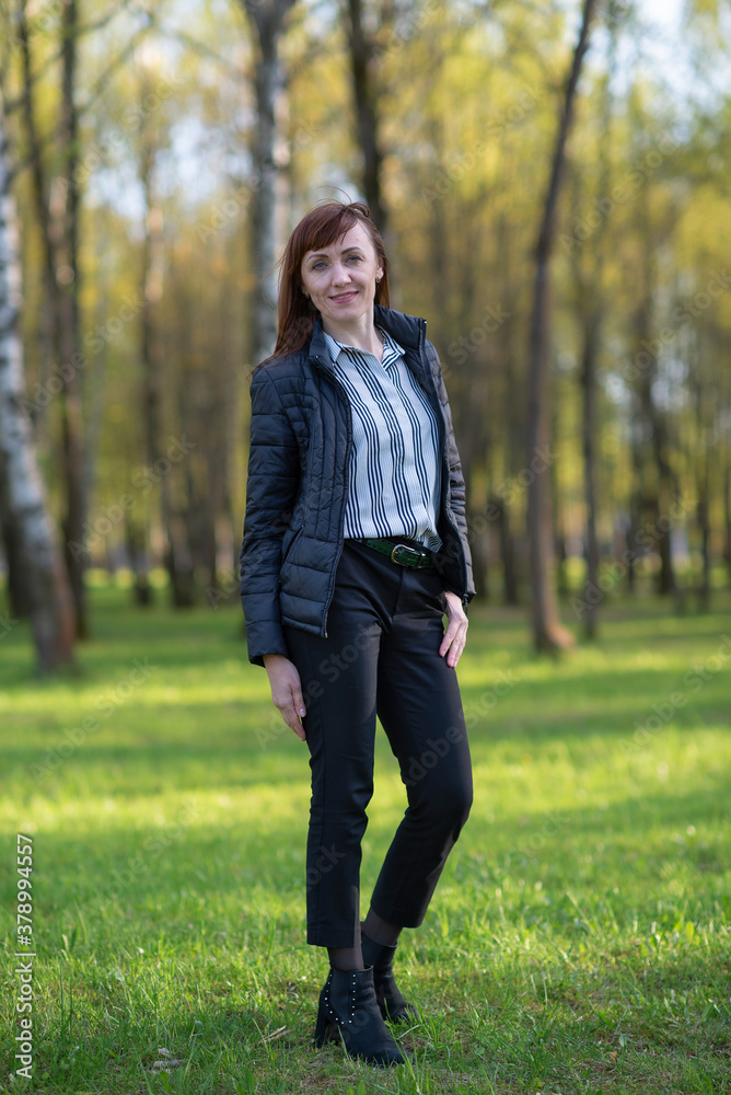 Young girl in trousers and a jacket posing in a spring park. Young girl in trousers and a jacket posing in a spring park.