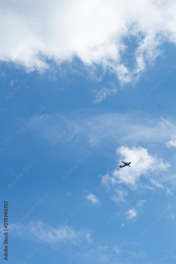 Fototapeta premium The airplane flies against the background of clouds in the blue sky