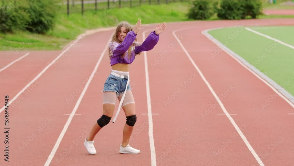 Girl dancer in short shorts dancing dancehall on a Sportsground. Performs spectacular elements of modern youth dance. Slow motion Girl dancer in short shorts dancing dancehall on a Sportsground. Performs spectacular elements of modern youth dance. Slow motion
