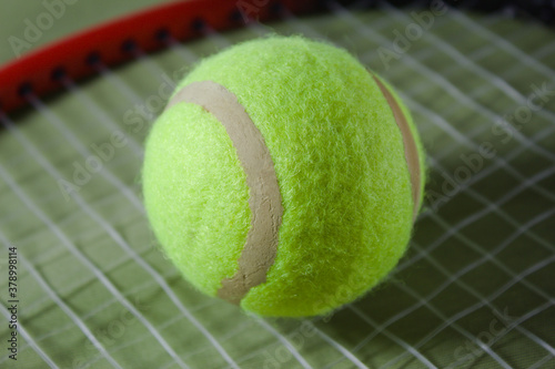 Tennis racket with ball on a green background