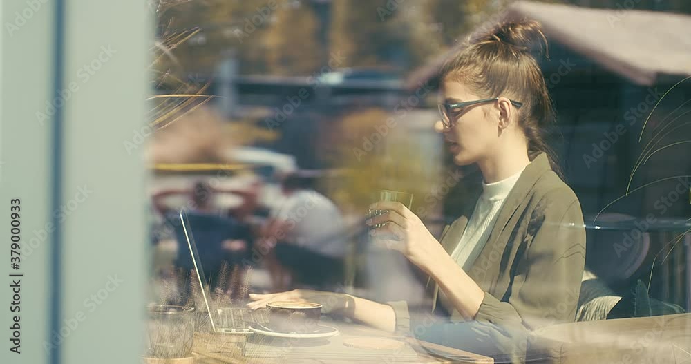 Woman working on tablet, sitting in cafe with cup of coffee. Girl in glasses pauses after work. Online chat with friends, long distance communication. Staying connected. 4K video