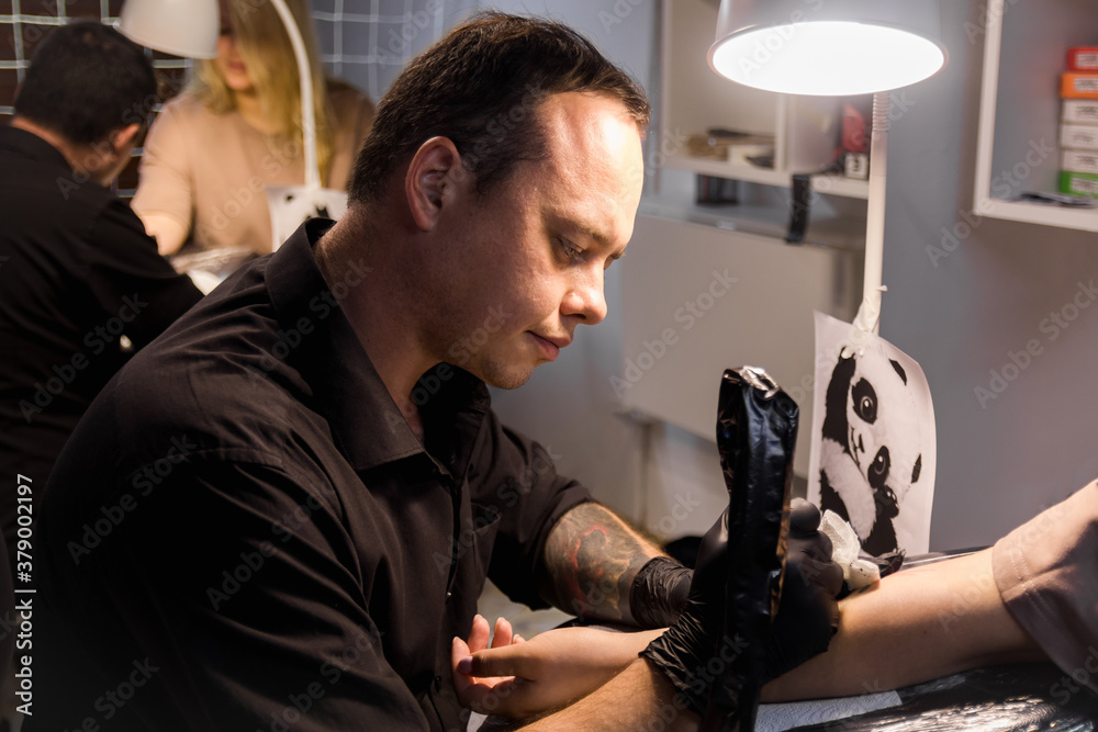 Master doing tattoo on hand