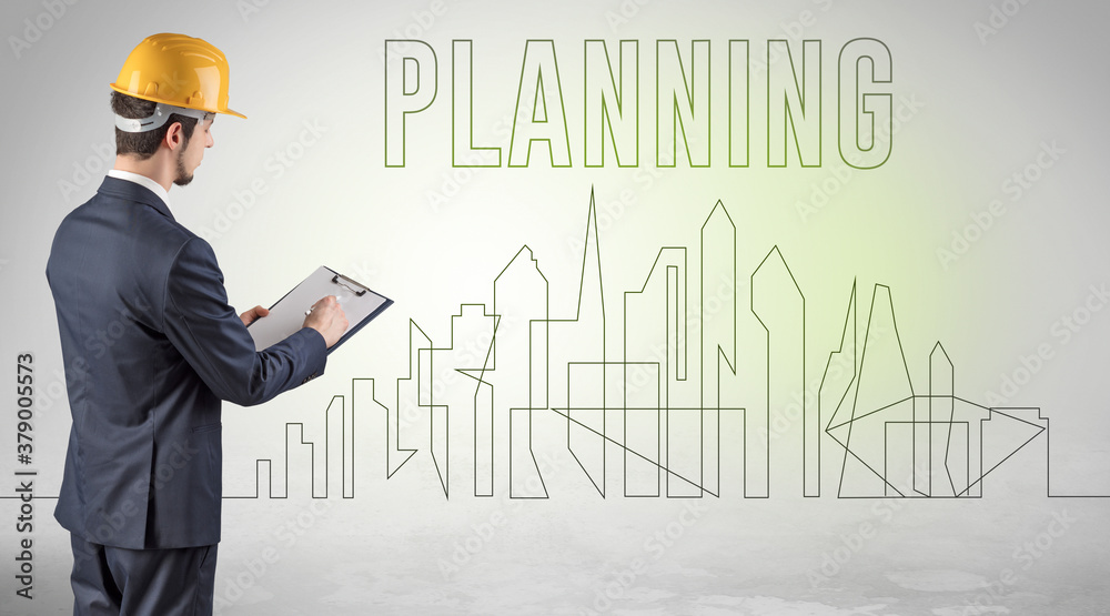 Businessman in hard hat holding blueprint with PLANNING inscription, engineering and architecture concept Businessman in hard hat holding blueprint with PLANNING inscription, engineering and architecture concept