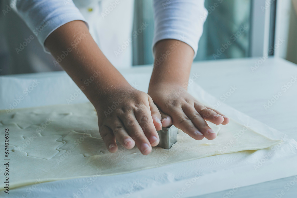 Child hands making christmas tree shaped cookies in fresh dough
