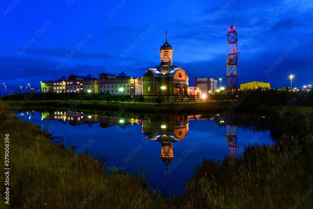 Russian orthodox church in Yamburg - small town in north of Russia at night time with reflection in water.