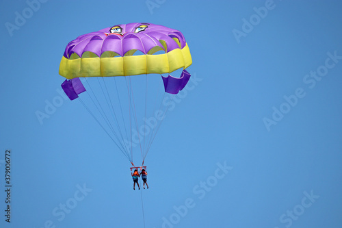 Parasailing on the sea, two girls on parashute in blue sky. Concept of vacation, extreme sports on a beach