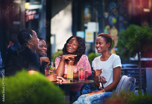 Happy African American Women, friends sitting together at the outdoor restaurant at summer day