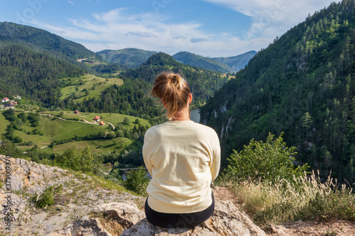Young girl in the nature. Back view portrait of a single woman watching the Spajici lake from the height in west Serbia
