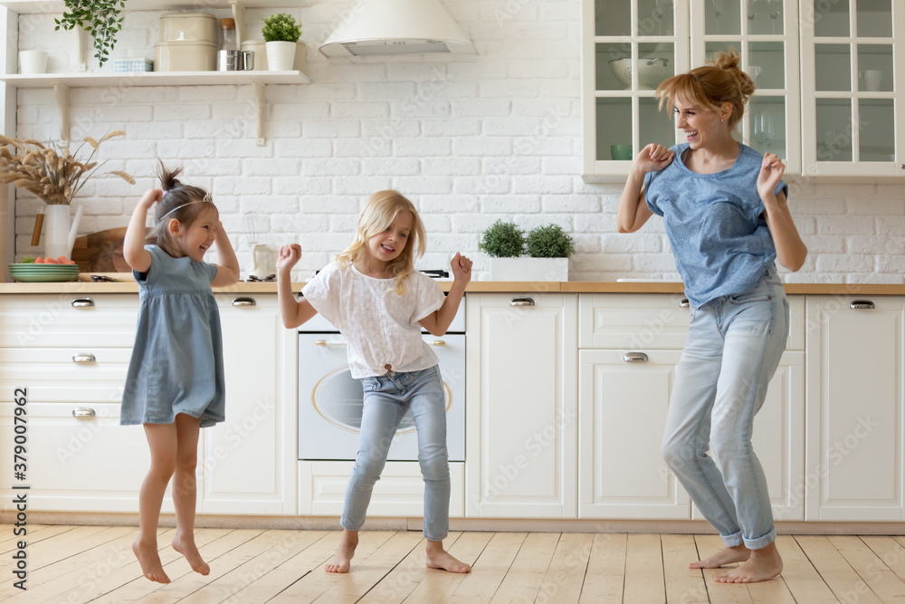 Φωτογραφία Happy mother and kids dancing and frolicking barefoot on wooden floor in cozy spacious kitchen