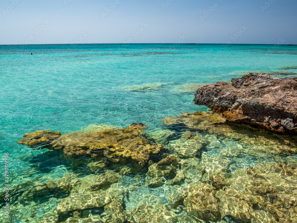 Elafonisi Crete Beach view to crystal clear water with nature rocks at the background