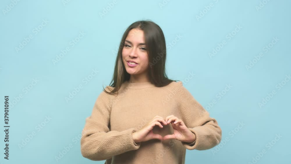 Young cute woman smiling and showing a heart shape with hands Young cute woman smiling and showing a heart shape with hands