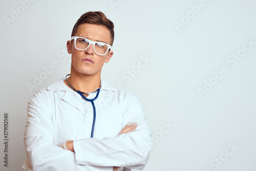 doctor in a medical gown with a stethoscope and glasses on a light background cropped view portrait © SHOTPRIME STUDIO
