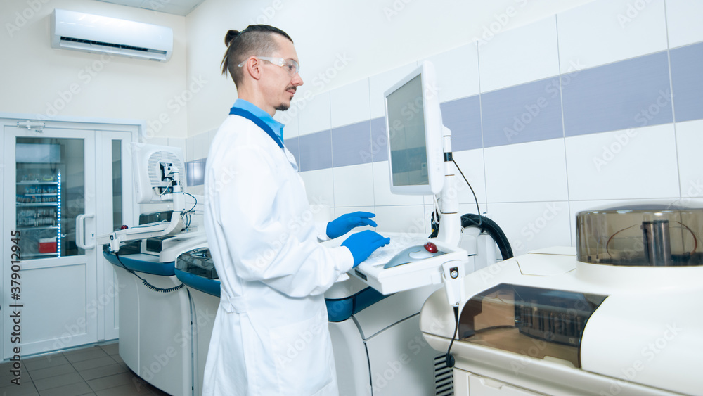 Laboratory assistant in rubber gloves working with a modern immunochemistry analyzer Laboratory assistant in rubber gloves working with a modern immunochemistry analyzer