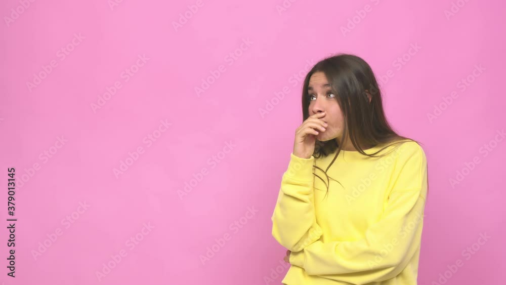 Young cute woman thoughtful looking to a copy space covering mouth with hand Young cute woman thoughtful looking to a copy space covering mouth with hand