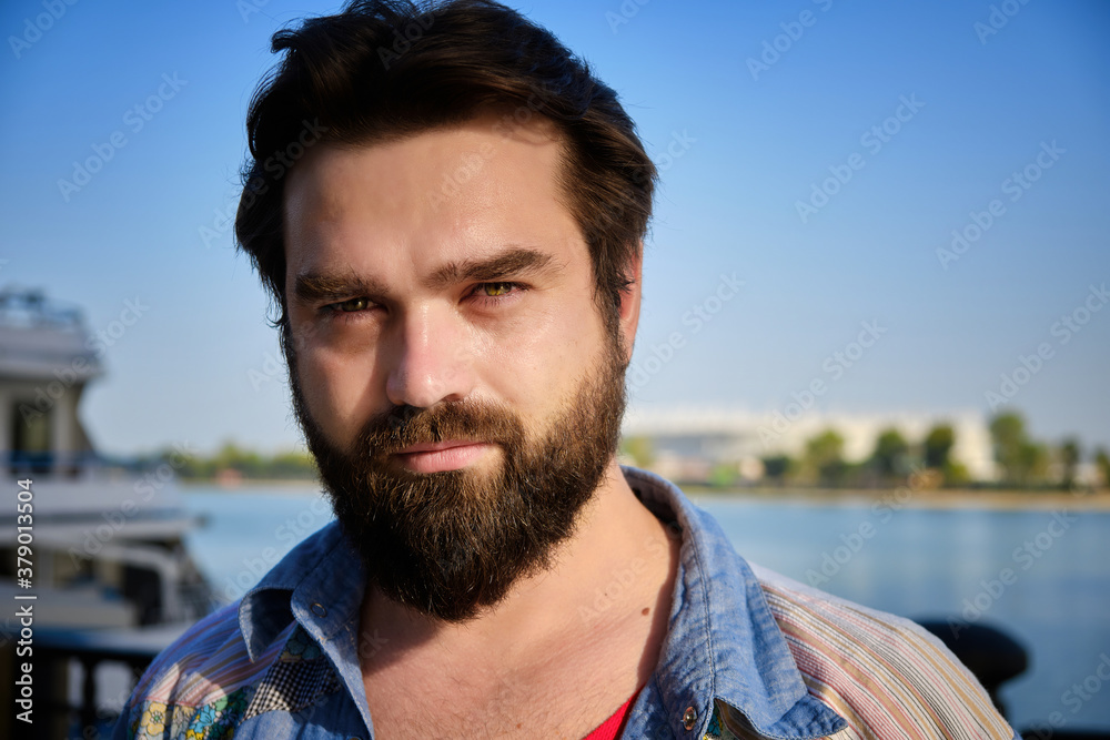 Portrait of bearded caucasian man with river and blue sky at background Portrait of bearded caucasian man with river and blue sky at background