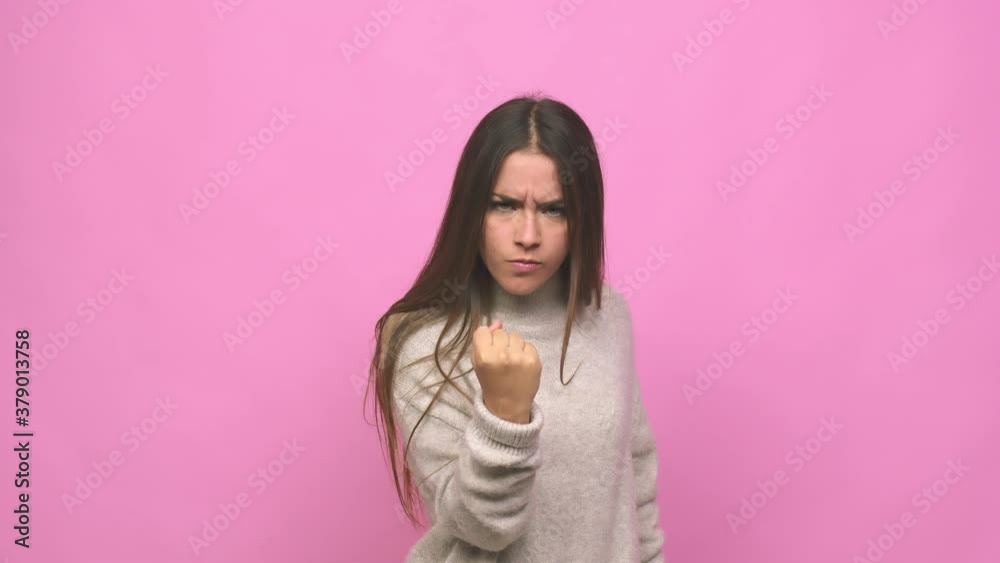 Young cute woman showing fist to camera, aggressive facial expression Young cute woman showing fist to camera, aggressive facial expression